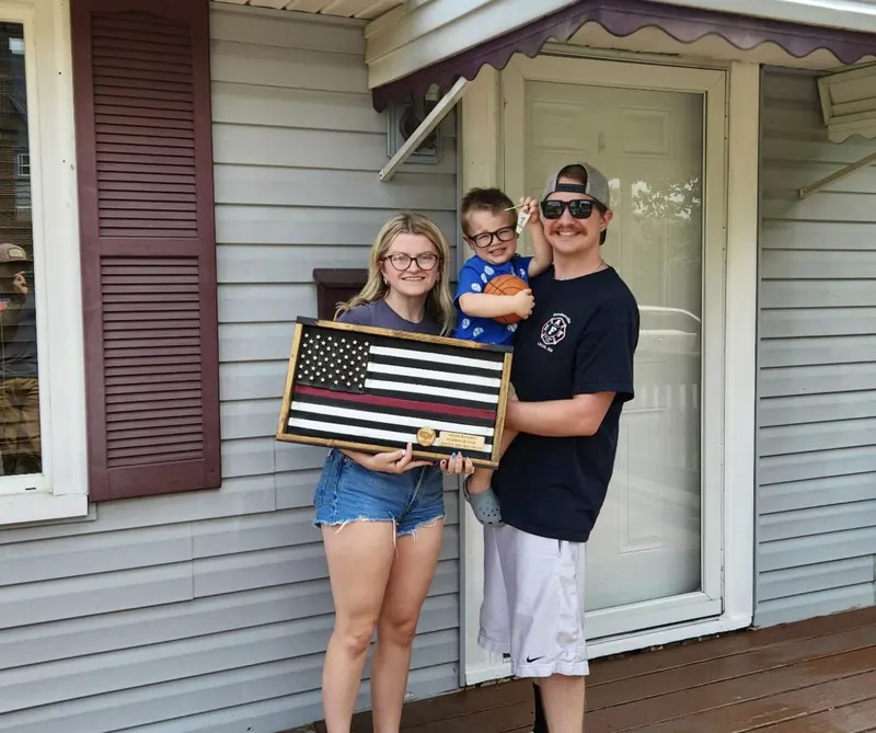 A Frontline client family outside their home with their fire hose flag