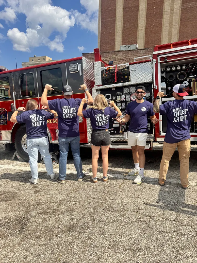 Frontline team members in matching shirts together beside a fire engine